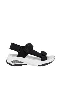 Sandales de sport noir et blanc avec une épaisse semelle blanche, un dessus texturé, des sangles ajustables et un rembourrage visible au niveau du talon.