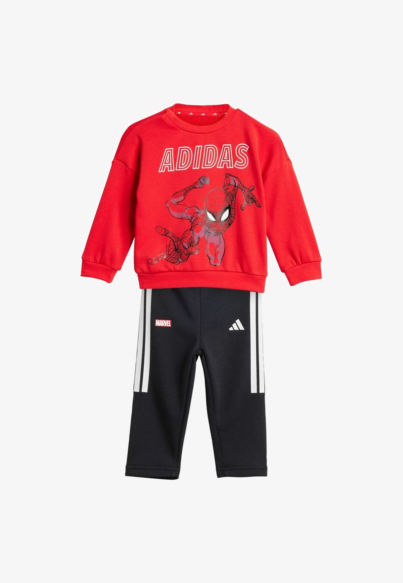 Felpa rossa con grafica di Spider-Man e testo "ADIDAS"; pantaloni neri con strisce bianche e logo "MARVEL". Composizione in cotone misto, vestibilità casual.