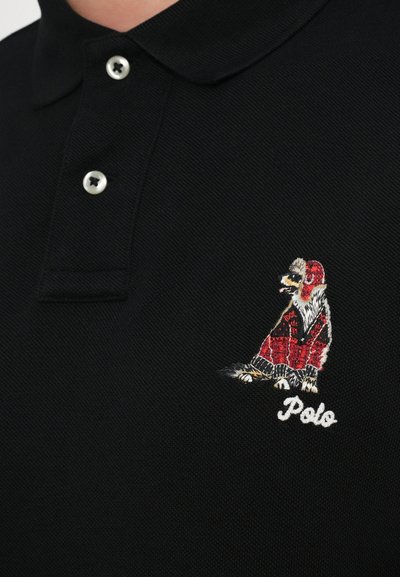 Črna polo majica z teksturirano tkanino, dvema gumboma in barvnim vezenim motivom psa s pisanimi dlakami ter besedo "Polo."