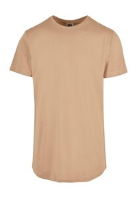 Beige tričko s krátkým rukávem, vyrobené z hladké látky, s kulatým výstřihem a prodlouženým lemem. Bez vzorů nebo ozdob.