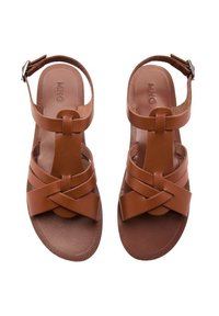 Sandali in pelle marrone con un design a strap incrociate, suola piatta, cinturino alla caviglia regolabile e suola texturizzata per una migliore aderenza.