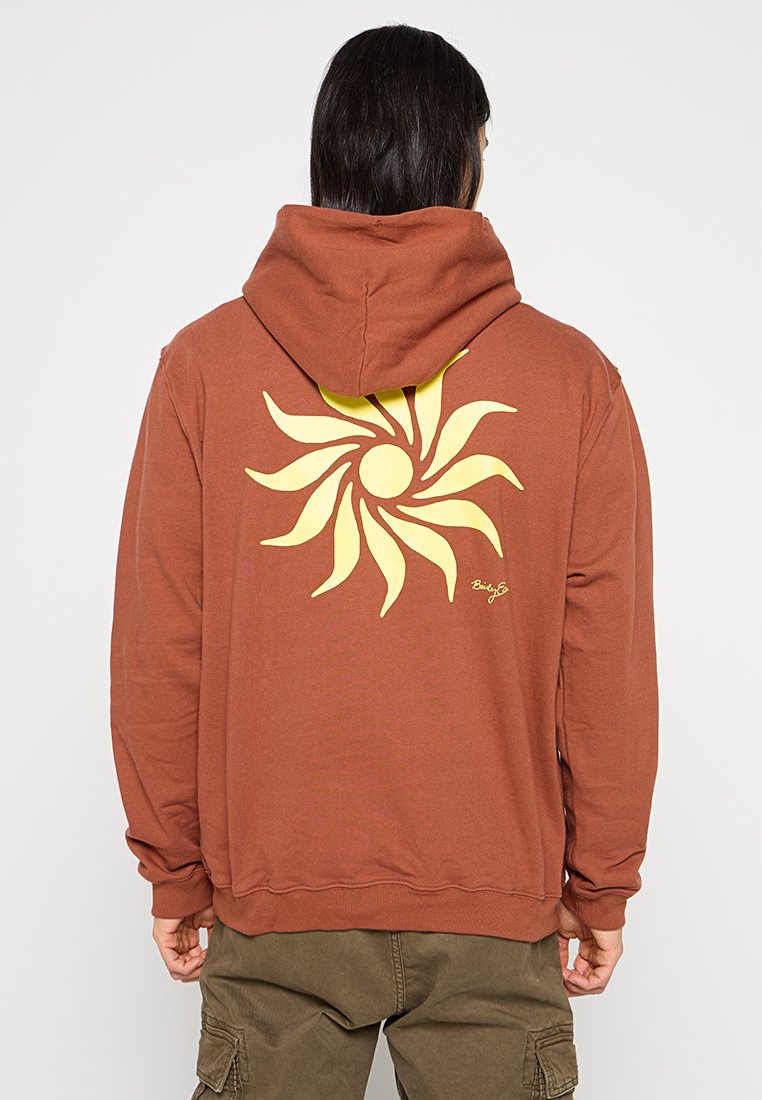 Hoodie marron en coton, présentant un grand graphique de soleil jaune au dos, avec une capuche à cordon de serrage et des poignets côtelés.