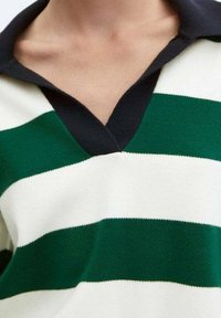 Polo shirt a righe verdi e bianche in maglia con colletto nero; presenta un design a scollo a V e una texture morbida.