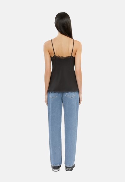 Svart sateng-camisole med blonderkant, parret med lyseblå rette jeans. Outfiten har tynne stropper og en avslappet passform.