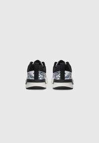 Sorte sneakers med et mønstrede hvidt og gråt tekstiloverdel, der har en glat sort sål og en bageste strop for nem påtagning.