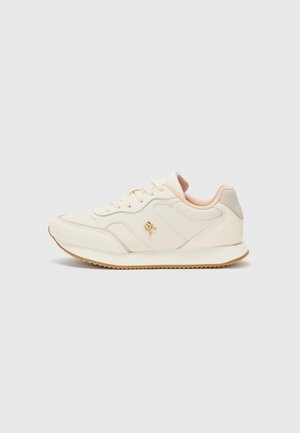 White athletic shoes with a smooth leather upper, light pink accents, and a gold logo. The outsole is gum rubber, featuring a textured grip pattern.