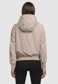 Beige bomber jakna s kapuljačom, izrađena od glatkog, sjajnog materijala, s elastičnim manžetama i pojasom, dizajnirana za opušteni kroj.