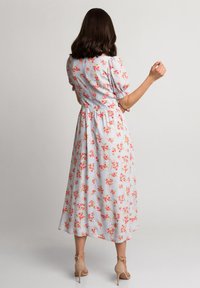 Kwiatowa midi sukienka z krótkimi bufkami, w jasnoniebieskim materiale ozdobionym różowymi kwiatami, z rzucającą się w oczy talią i zwiewnym dołem.