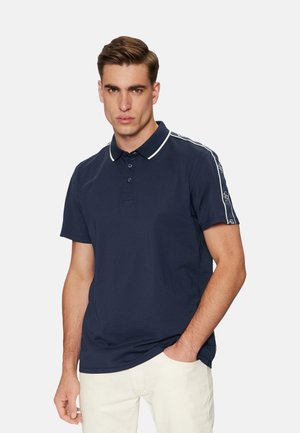 Camisa polo color navy con acentos en blanco, tres botones y mangas cortas. La tela parece suave con un brillo sutil y detalles de logotipos en los costados.