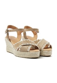 Beige suède wedgesandalen met open teen, enkelbandje en decoratieve stiksels. Jute-wrapped platform en hak voor textuur en stabiliteit.