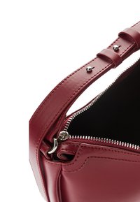 Rote Lederhandtasche mit glatter Oberfläche, ausgestattet mit einem Reißverschluss oben, silberner Hardware und einer strukturierten Form mit einem kurzen, verstellbaren Riemen.