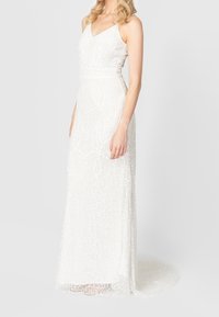 Biała suknia z dopasowanym gorsetem na cienkich ramiączkach, ozdobiona szczegółowym koralikowym haftem i zwiewną spódnicą, kończącą się subtelnym trenem.