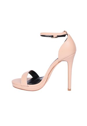 Sandalo beige con tacco alto, cinturino alla caviglia e punta aperta su sfondo bianco.