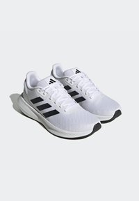 Scarpe sportive bianche con tomaia in rete, design a tre strisce nere, suola imbottita e soletta in gomma nera. Include lacci e colletto imbottito.