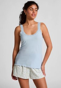 Lichtblauw geribd tanktopje met kanten rand, gecombineerd met witte shorts met kleine blauwe bloemenpatronen. Zachte stof en comfortabele pasvorm.