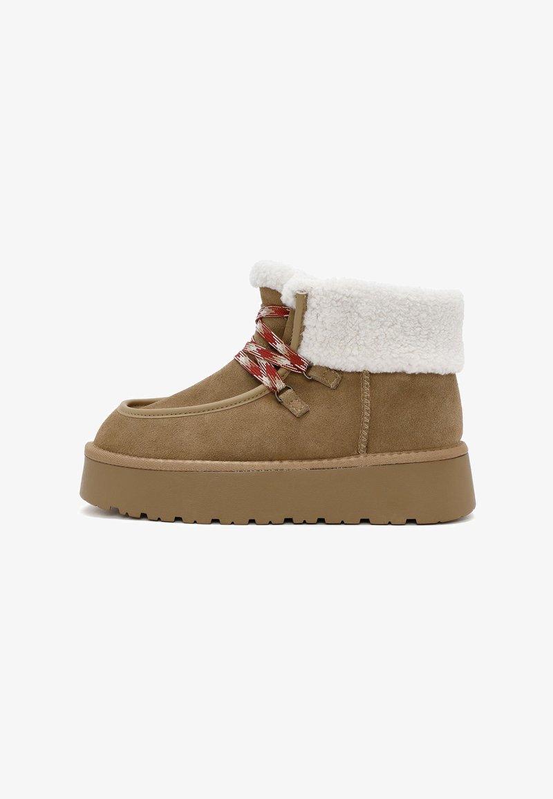 Brown suede ankle boots with a white faux fur collar, featuring red and white patterned laces and a thick rubber sole.