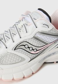 Baskets blanches en mesh et matériaux synthétiques, avec des accents gris, des détails noirs et des touches de rose sur la semelle et le logo.