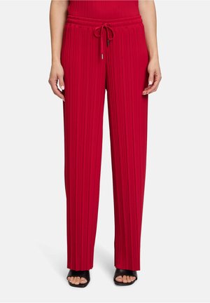 Rote plissierte Hose mit elastischem Bund und Kordelzug, mit weitem Beinanschnitt und glatter Textur, kombiniert mit schwarzen High-Heelsandalen.