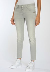 Ljust grå skinny jeans i denim med en slät yta, som har framfickor, knappstängning och en slim fit. Kombineras med vita sneakers.