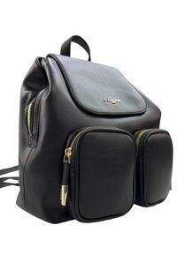 Zaino in pelle nera con patta frontale, due tasche con zip, dettagli in metallo dorato e spallacci regolabili. Texture liscia, forma arrotondata.