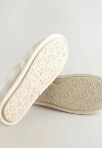 Light grey wool slippers with a textured beige rubber sole featuring a star and crescent moon pattern. Soft fabric upper, slip-on design.
