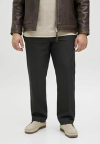 Black, straight-leg trousers made of smooth fabric. Paired with a beige top and brown leather jacket, complemented by light-colored shoes.