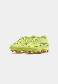 Sárga-zöld Nike focicipő pár fekete swoosh logókkal és narancssárga stoplikkal fehér háttéren.
