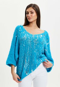 Blue fuzzy sweater with an oversized fit, featuring silver sequins. Wide neckline and loose sleeves, textured knit with soft appearance.