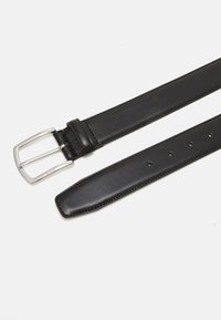 Ceinture en cuir noir avec une boucle rectangulaire en argent, présentant une texture lisse et plusieurs trous pour l'ajustement de la taille.