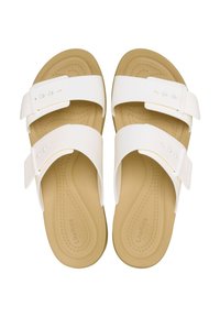 White slide sandals featuring two adjustable straps with a smooth finish, cushioned tan footbed, and textured sole for traction.