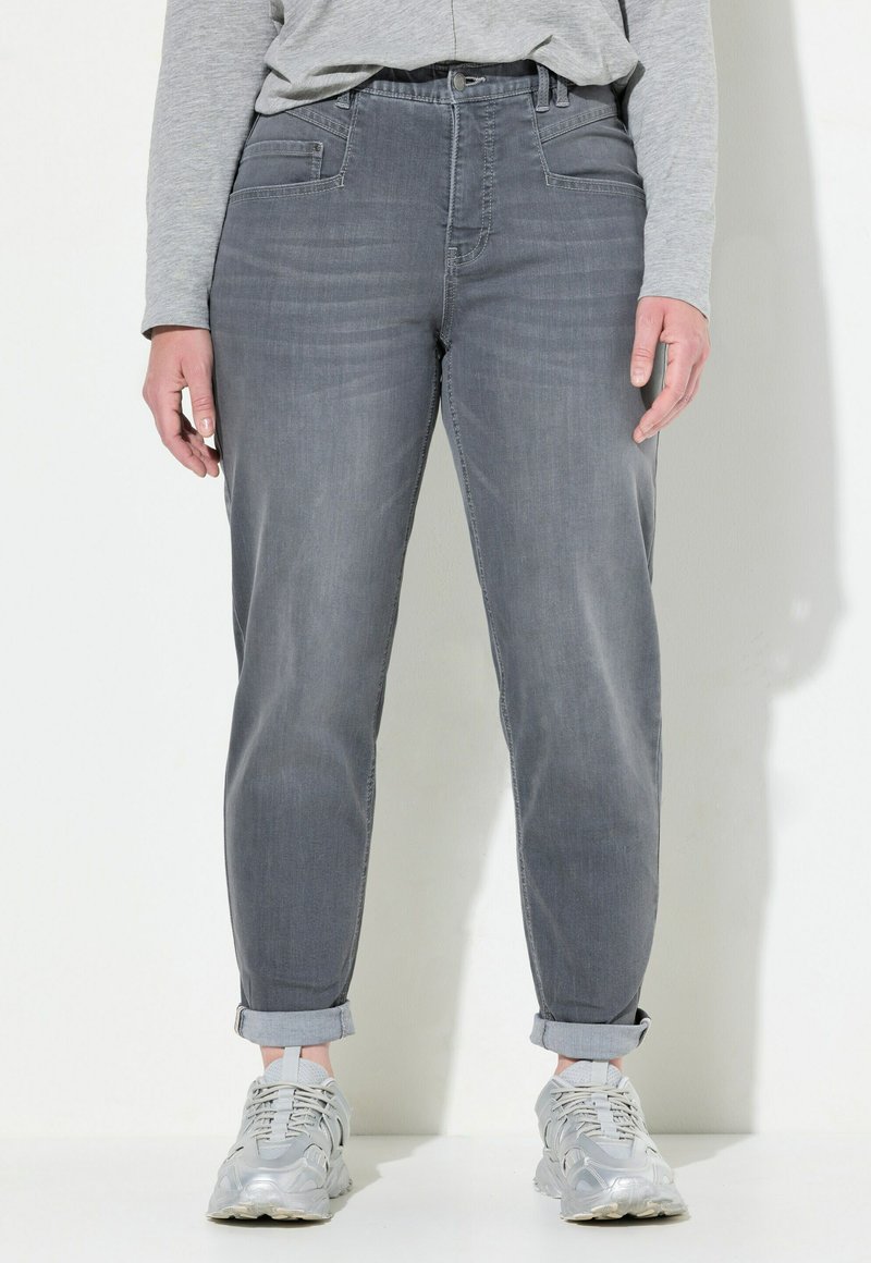 Jeans de mezclilla gris con un corte relajado, con dobladillos enrollados, bolsillos delanteros y una textura suave. Combinados con zapatillas gris claro.