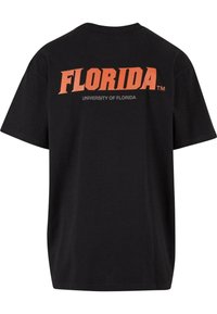Black cotton t-shirt featuring bold orange text "FLORIDA" and "UNIVERSITY OF FLORIDA" printed on the back in a smaller grey font.