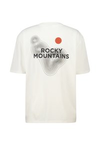 Valkoinen t-paita, jossa on mustalla tekstillä "ROCKY MOUNTAINS", punainen ympyrä ja aaltoilevat käyräkuviot takana. Silkkinen puuvillakangas.