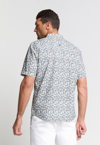 Korte mouw shirt in een veelkleurig geometrisch patroon met blauwtinten, grijs en beige; gemaakt van lichtgewicht stof, met kraag en knoopdetails.