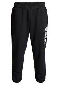 Zwarte joggingbroek van zacht materiaal, met een elastische tailleband, zijzakken en een wit logo dat langs het linkerbeen is gedrukt.
