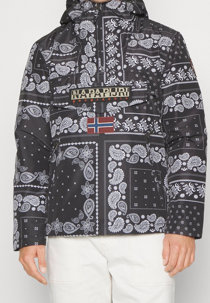 Zwarte jas met een patroon van witte paisleyprints, een klepzak met de tekst "Napapijri geographic" en een Noorse vlagpatch op de borst.