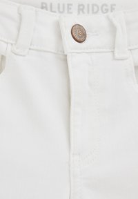 Vita denimjeans med en klassisk femficksdesign, metallknappstängning och subtilt strukturerad tyg. Varumärkesetikett synlig ovanför.