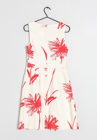 Vit klänning med ett djärvt rött blommönster, ärmlös design, rund halsringning och dragkedja bak. Utsvängd kjol med sidofickor.