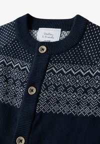 Navyblauer Strickcardigan mit einem weißen geometrischen Muster, Rundhalsausschnitt und zwei beigen Knöpfen an der Vorderseite. Der Stoff hat eine glatte Textur.
