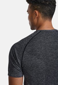 Kortärmad sporttröja i mörkgrått med texturerat tyg, raglanärmar och rund halsringning. Dekorerad med kontrastsömmar.