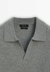 Pull en laine côtelée gris avec un col ouvert et une étiquette "Massimo Dutti" cousue à l'intérieur de l'encolure.