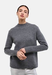 Pull en laine gris avec un col rond, des poignets et un ourlet côtelés. Présente un motif en maille texturée et une coupe décontractée.
