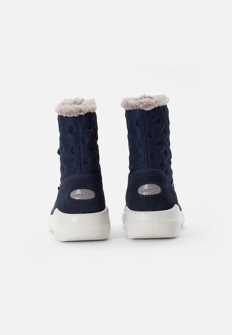 Bottines bleu marine avec doublure grise en peluche, tige texturée avec des motifs circulaires, semelles en caoutchouc blanches et logo "superfit" à l'arrière.