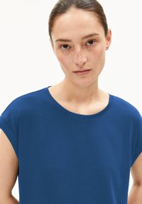T-shirt en coton bleu avec un col rond et des manches courtes, présentant une texture lisse et une coupe décontractée. Aucun motif ou accent visible.