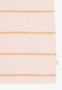 Un tessuto a righe rosa chiaro presenta due strisce orizzontali arancioni. La texture appare morbida con un leggero effetto melange. Piccola etichetta del marchio visibile.