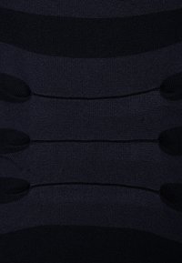 Leggings de compression bleu marine foncé avec une texture côtelée horizontale. Matériau lisse avec des rayures et sections de largeurs variées.