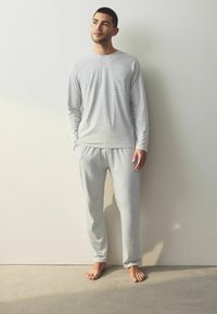 Grijs lang mouwshirt met een borstzak en bijpassende grijze broek. Beide zijn gemaakt van een zachte, lichtgewicht stof, met een ontspannen pasvorm.