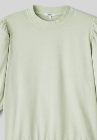 Pull-over léger vert en coton doux, présentant un col ras du cou et des manches longues bouffantes avec des accents froncés.