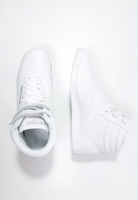 Witte sneakers met een gladde synthetische bovenkant, geperforeerde teen, vetersluiting aan de voorkant en gevoerde kraag; platte rubberen zool met een minimaal ontwerp.