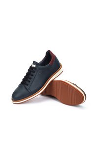 Zapatillas de deporte de cuero azul oscuro con cordones negros, acento burdeos en el talón, entresuela blanca y suela de goma marrón con estrías.